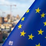 Drapeau de l'UE sur fond urbain industriel flou.