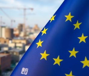 Drapeau de l'UE sur fond urbain industriel flou.